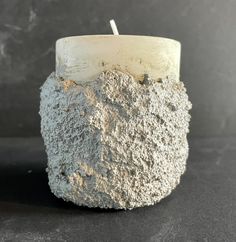 a candle that has been made out of cement and is sitting on a black surface