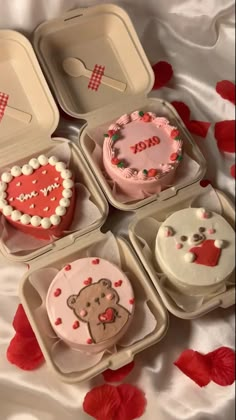 four heart shaped cupcakes in small trays on a bed