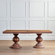 a wooden table sitting on top of a hard wood floor next to a white wall