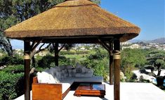 an outdoor gazebo with couches and tables in the foreground