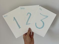 someone is holding up three numbered cards with numbers on them