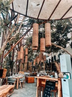 the inside of a restaurant with wooden tables and hanging bamboo baskets on the ceiling, surrounded by palm trees