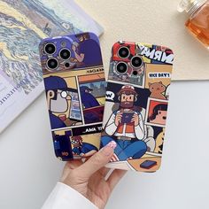 someone holding up two cell phones with cartoon pictures on them, one has a phone case and the other has an iphone