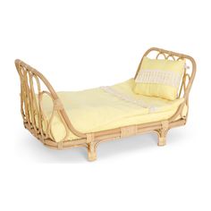 a wicker bed with yellow sheets and pillows on the bottom, in front of a white background