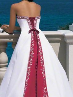 a woman in a white and red wedding dress standing on a balcony overlooking the ocean