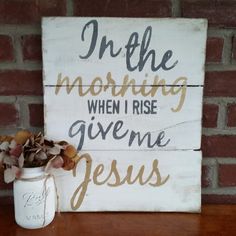 a mason jar sitting on top of a wooden table next to a sign that says, in the morning when i rise give me jesus