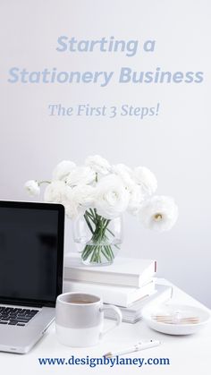 a laptop computer sitting on top of a desk next to a vase filled with white flowers