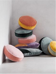 a pile of pillows sitting on top of a white floor next to a gray wall