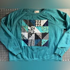 A Thrifted Crewneck Sweater, In Teal, Size Xlarge. Custom Made Quilt Square On The Center Front Of Jumper. Various Fun Fabrics, And One Featuring A Cute Cat! Stand Out In Style, In A Sustainable And Unique Way! Measurements In Photos: Total Length 23.5 Inches, Pit To Pit 24 Inches. Casual Raglan Sleeve Tops With Patchwork, Quilt Square Sweatshirt, Quilt Applique Sweatshirt, Thrifted Crewneck, Cat Stand, Fur Lined Hoodie, Quilted Sweater, Fuzzy Hoodie, Applique Sweatshirt