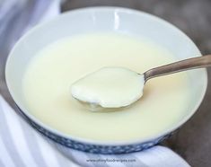 a spoon full of milk sitting on top of a bowl