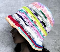 a woman wearing a multicolored crocheted hat on top of a mannequin head