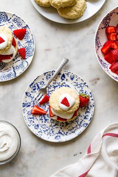 strawberry shortcakes with whipped cream and strawberries in bowls on a marble table