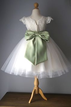 a white dress with a green bow on it