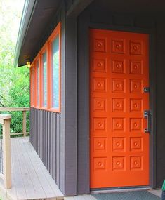 an orange front door on a gray house