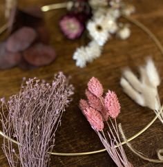 dried flowers are arranged on a wooden table with metal wire and wood slices in the background