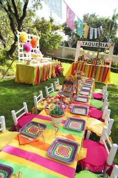 an outdoor table set up for a party with place settings and colorful napkins on it