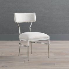 a white chair sitting on top of a hard wood floor next to a gray wall