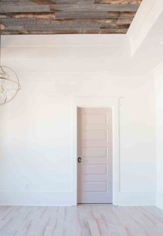 an empty room with white walls and wood flooring in the center is a light fixture