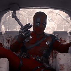 deadpool sitting in the back seat of a car with blood all over his body