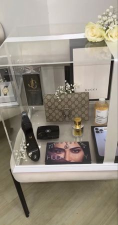 an assortment of perfumes and personal care items on display in a glass case with flowers