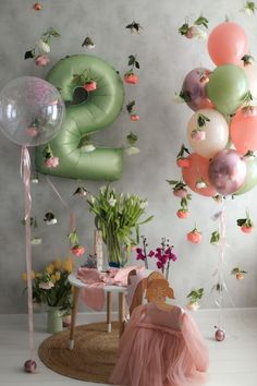 balloons are floating in the air next to a table with a cake and flowers on it