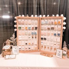 two display boards with earrings on them sitting on a table in front of a curtain