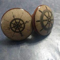 two wooden knobs with an image of a ship's wheel and compass on them