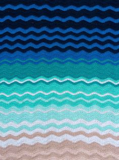 a knitted blanket with wavy waves in blue, brown and green colors on it