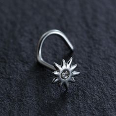 a silver ring with a diamond in the center on a black surface, close up