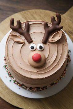 a chocolate cake with frosting decorated as a reindeer's head on a wooden table