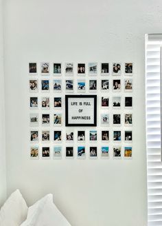 a white bed sitting under a window next to a wall with pictures hanging on it