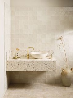 a white sink sitting next to a vase filled with flowers