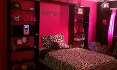 a bedroom decorated in pink and black with zebra print on the bed, bookshelves and shelves