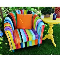 a colorful chair sitting on top of a green grass covered field next to a yellow table