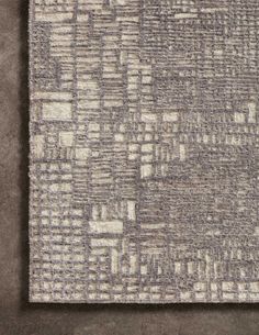 a gray and white rug on top of a floor with a grey wall in the background