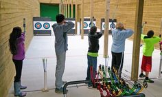 several children are practicing archery in an indoor gym