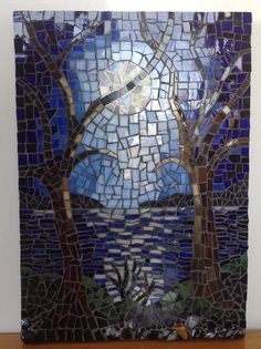 a piece of art made out of stained glass with trees and sky in the background