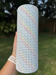 a person holding up a large white object with multicolored dots on it's side