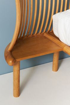 a wooden bed frame sitting on top of a white floor next to a blue wall