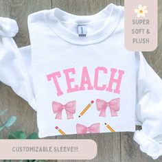 Custom Teacher Coquette Sweatshirt, Balletcore Pink Bow Sweater, Graduation Shirt, Writing Professor Crewneck, Teacher Appreciation Gift Personalizable teacher name on sleeve Or leave it blank This high-quality heavy blend crewneck sweatshirt is pure comfort and warmth. Made from polyester and cotton. No itchy side seams! Please reference all the photos for details and sizing :) ALL SALES ARE FINAL. Please read our return policy. Relaxed Fit Long Sleeve School Top, White Fitted Cotton Sweatshirt, Relaxed Fit Long Sleeve T-shirt For School, White Tops For School In Fall, Long Sleeve Pink Tops For School, Long Sleeve School Shirt With Graphic Print, Long Sleeve Graphic Print School Shirt, Fitted Long Sleeve Shirt With Custom Print, Pink Long Sleeve T-shirt For School