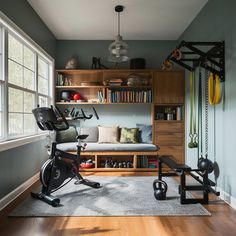 a home gym with exercise equipment and bookshelves in the corner, next to a window