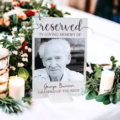 an old man is sitting in front of a memorial sign with candles and flowers around it