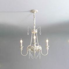 a chandelier hanging from the ceiling in a room with white walls and flooring