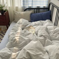 an unmade bed with two pillows and a book on the pillowcase next to it