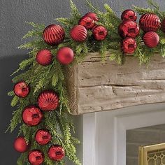 a decorated mantle with red ornaments and greenery