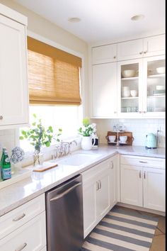 a kitchen with white cabinets and black and white striped rug on the floor in front of the dishwasher