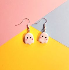 a pair of cute little ghost earrings on a yellow and pink background