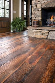 an image of a living room with wood flooring and stone fireplace in the center