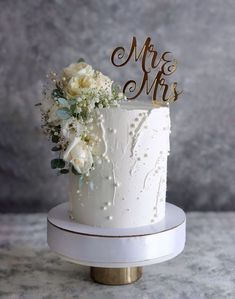 a white wedding cake with gold mr and mrs topper