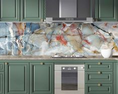 a kitchen with green cabinets and marble backsplash, stainless steel range hood over the stove